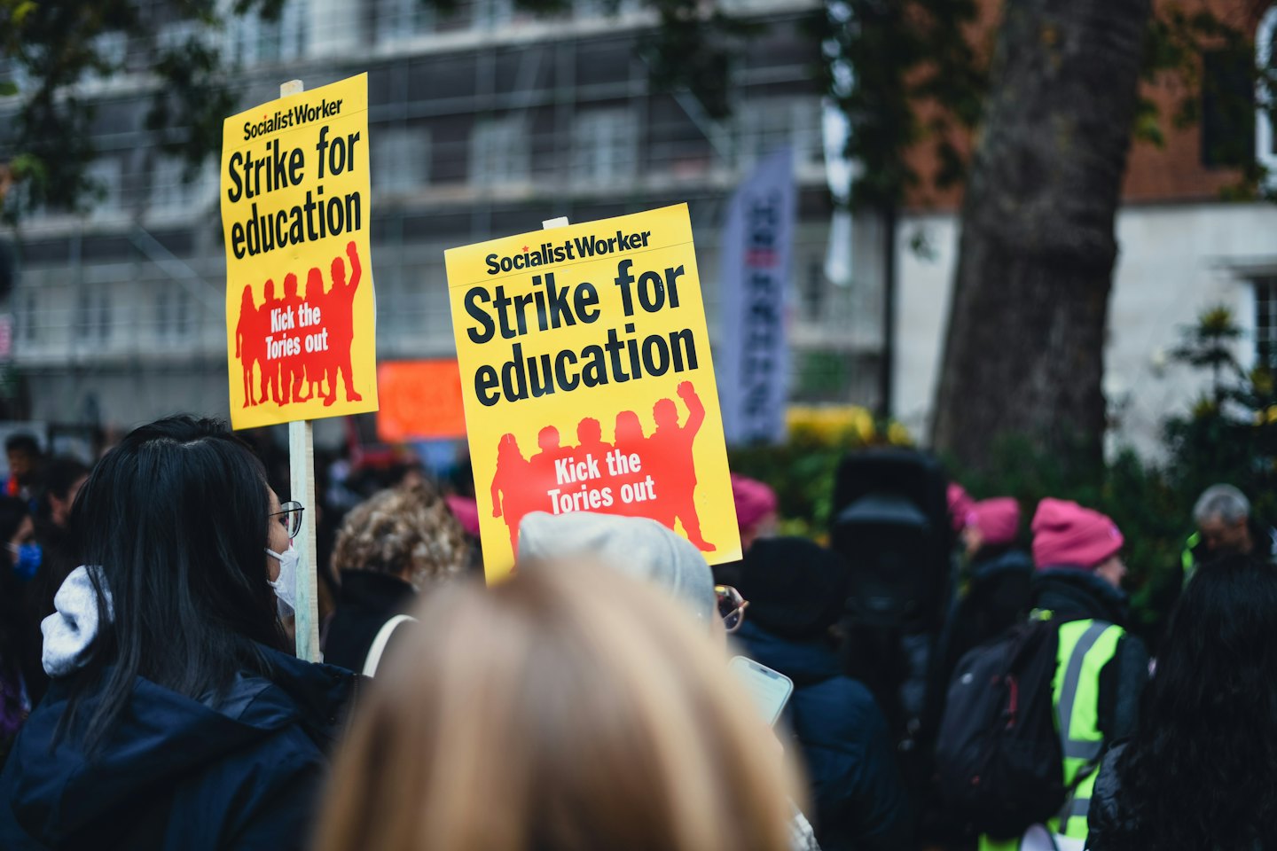 Protestors hold yellow signs during a political demonstration outdoors.