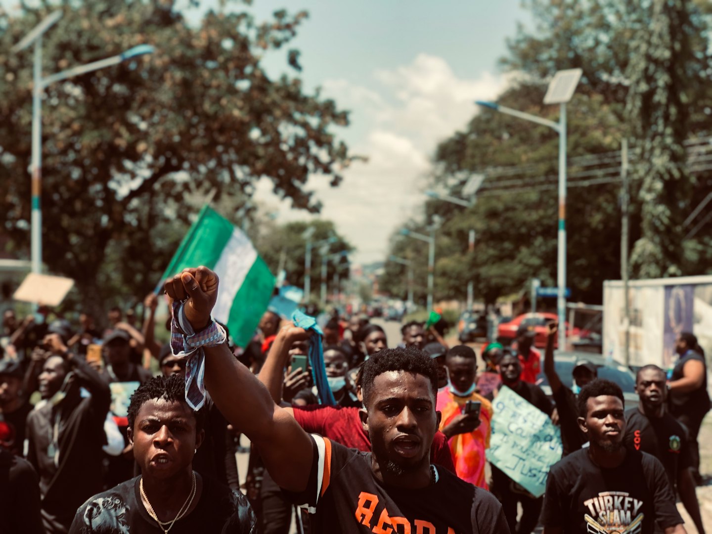 Protesters raise fists in solidarity holding a Nigerian flag.