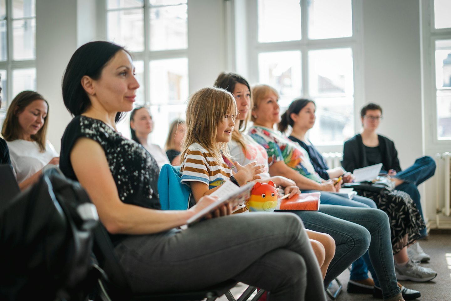 Girl gestures enthusiastically at an indoor business seminar.